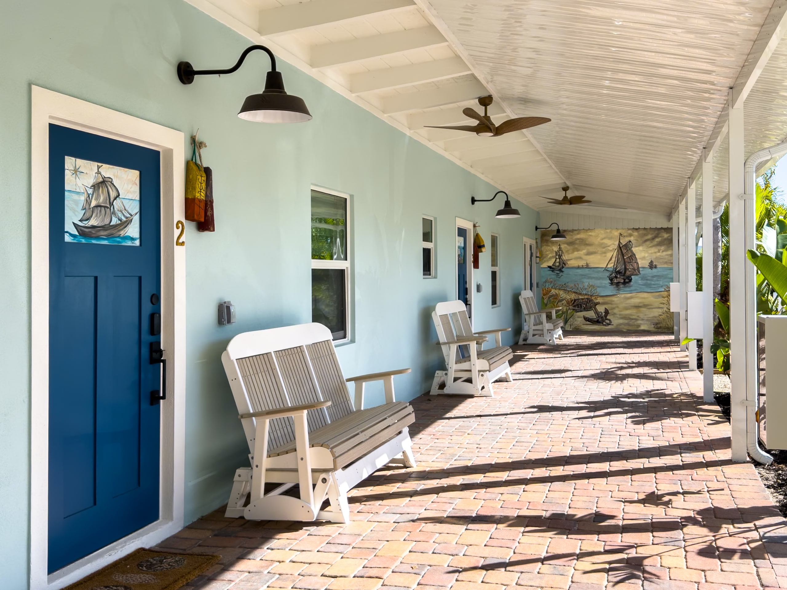 Exterior guest room corridor at the renovated Anchor Inn & Cottages on Sanibel Island with rocking chairs and coastal decor.
