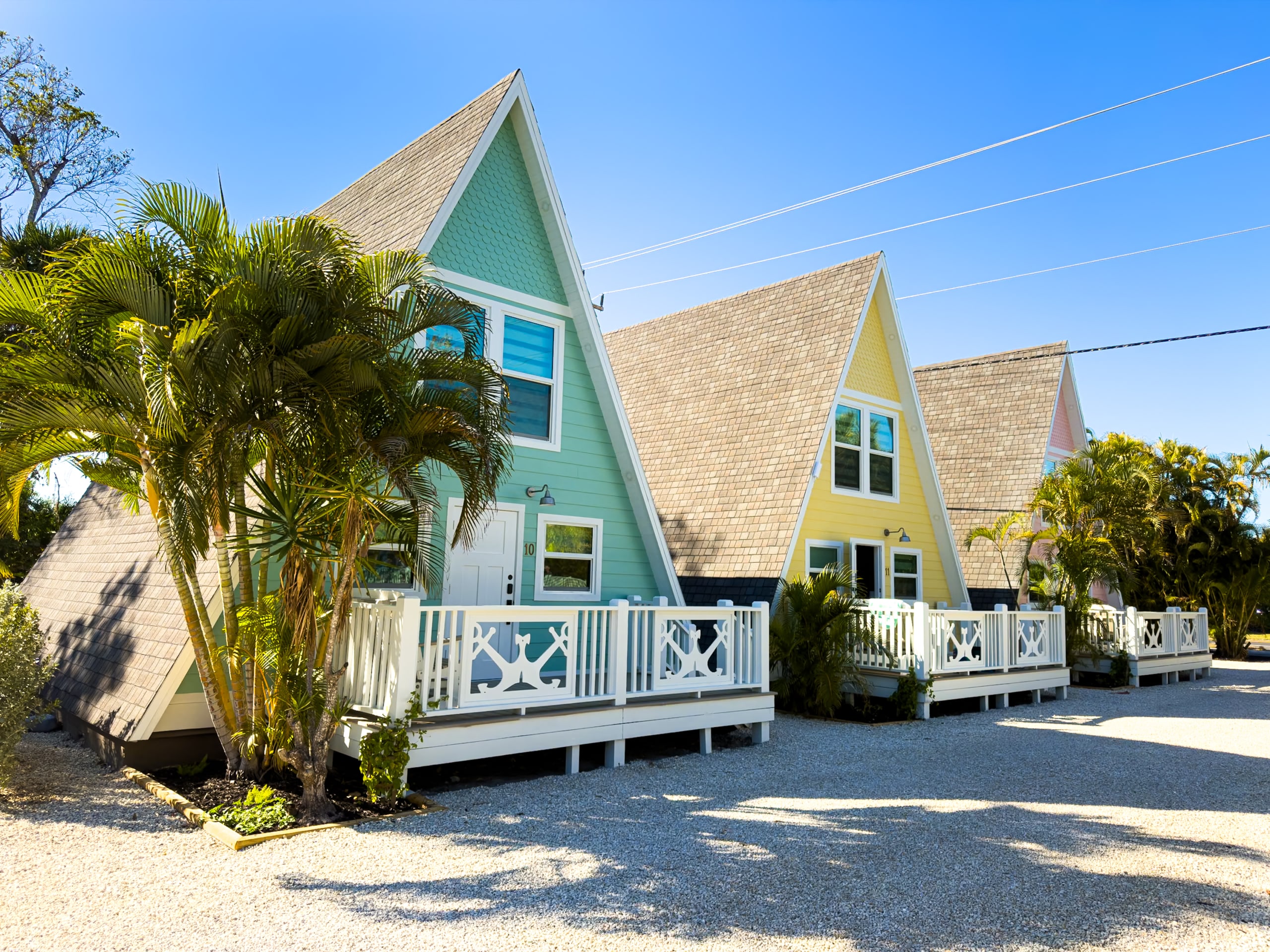 Colorful newly renovated Anchor Inn & Cottages A-frame cottages on Sanibel Island with palm trees and private porches.